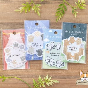 Puede incluir: Cuatro paquetes de notas adhesivas de colores con ilustraciones de osos y pandas. Las notas están decoradas con texto japonés y tienen un diseño caprichoso.