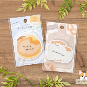 Puede incluir: Dos paquetes de blocs de notas de 30 hojas con adorables ilustraciones de corgis. El primer paquete tiene un corgi con un panqueque y el texto "¿Almorzar juntos?" El segundo paquete tiene dos corgis abrazándose y el texto "Acaríciame la pancita".