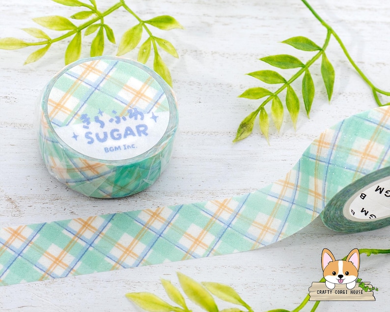 Pode incluir: Um rolo de fita washi com um padr&atilde;o xadrez verde e branco. A fita tem as palavras "Sugar BGM Inc." impressas nela.