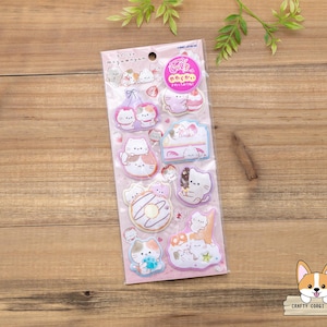May include: A sheet of stickers featuring cartoon cats in various poses, including holding desserts and sitting on clouds. The stickers are in pastel colors with a pink background and are packaged in a clear plastic sleeve.