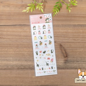 Op de afbeelding: Een vel stickers met personages uit de animatiefilm "Kiki's Bezorgservice". De stickers zijn op een witte achtergrond met roze randen en bevatten verschillende personages, waaronder Kiki, Jiji de kat en Tombo. De stickers zijn gelabeld met "Schedule Seal".