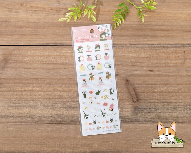 Op de afbeelding: Een vel stickers met personages uit de animatiefilm "Kiki's Bezorgservice". De stickers zijn op een witte achtergrond met roze randen en bevatten verschillende personages, waaronder Kiki, Jiji de kat en Tombo. De stickers zijn gelabeld met "Schedule Seal".