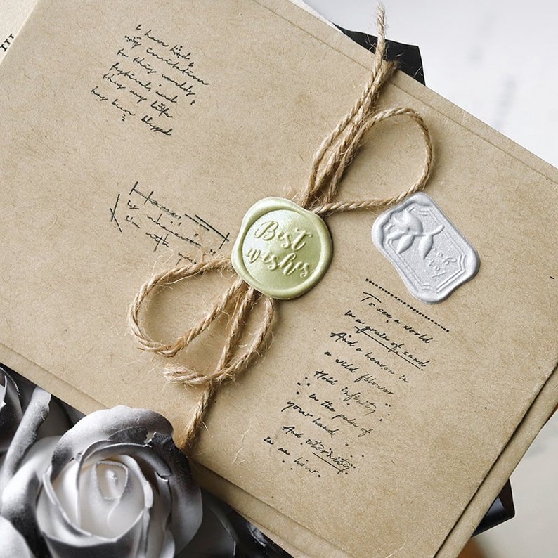 May include: A brown paper package tied with twine and sealed with a gold wax seal that says "Best Wishes" and a silver wax seal with a leaf design. The package has a handwritten message that reads "To see a world we are a grain of sand. And a heaven in a wild flower... hold infinity... in the palm of your hand... And eternity... in an hour."