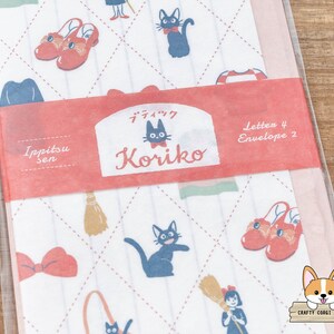May include: A set of 4 letter writing papers and 2 envelopes featuring a whimsical design with a black cat, red shoes, a broom, and a bow. The paper is white with a pink and green checkered pattern. The text on the paper reads "Ippitsu sen" and "Koriiko".