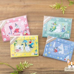 Peut inclure: Quatre ensembles de papeterie carrés et colorés avec des personnages de dessins animés. Chaque ensemble a une couleur de fond différente : rose, vert, jaune et bleu. Les ensembles sont emballés dans du plastique transparent et sont disposés sur une surface en bois.
