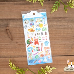 May include: A sheet of colorful stickers featuring summer-themed illustrations, including a watermelon, a bug, a hat, a bucket, a watering can, a flower, and a dragonfly. The stickers are on a blue background with white clouds.