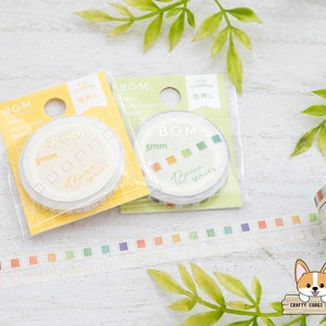 Può includere: Tre rotoli di nastro washi con un motivo quadrato dorato e il testo "Basic series" su sfondo bianco. Il nastro è largo 5 mm. I rotoli sono confezionati in plastica trasparente con un'etichetta bianca che dice "BGM" e "5 mm".