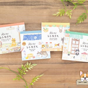 May include: Four colourful memo pads with illustrations of cats and the text "Nekorobi Retro Memo" in Japanese. Each pad features a different cat design and a different Japanese phrase.