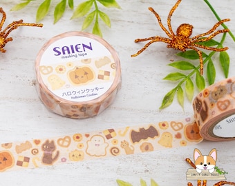 Puede incluir: Un rollo de cinta adhesiva decorativa Saien con un patrón de galletas temáticas de Halloween, incluyendo calabazas, fantasmas, murciélagos y gatos. La etiqueta muestra el texto Saien masking tape, Halloween Cookies y caracteres japoneses.