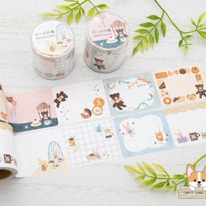 Puede incluir: Rollos de cinta washi y cuadrados de papel estampados con ilustraciones de osos, conejos, rosquillas y tazas de té. La paleta de colores incluye rosas, azules y marrones suaves, perfectos para proyectos de scrapbooking y manualidades.