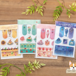 Può includere: Quattro fogli di nastro washi con motivi colorati con vari design, tra cui un tema dessert, un tema spaziale e un tema floreale. Ogni foglio ha uno sfondo di colore diverso e presenta una varietà di illustrazioni carine.