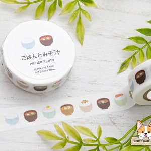 May include: A roll of washi tape with a white background and illustrations of bowls of rice and soup. The tape is labeled "ごはんとみそ汁" and "PAPIER PLATZ masking tape W15mmx10m".