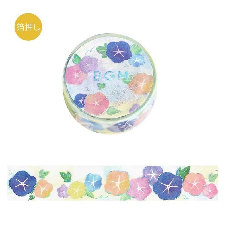 May include: A roll of decorative washi tape featuring a floral design with blue, pink, and yellow morning glories. The tape roll has the text "BGM" and a cursive script. A strip of the tape shows the repeating floral pattern.