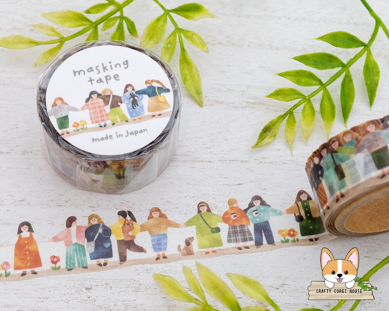 May include: Masking tape roll with a repeating illustration of people holding hands. The tape roll has the words "masking tape" and "Made in Japan" printed on it. The tape is decorated with a floral and green leaf design.
