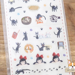May include: A sheet of stickers featuring illustrations of black cats, a girl with a red bow, and other related imagery. The stickers include various poses of cats, food, and a radio. The stickers are on a white background.