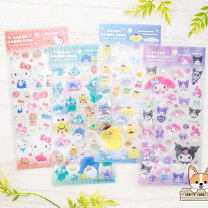 May include: Four sheets of clear candy seals featuring various cartoon characters. The sheets are in pink, green, blue, and purple. Each sheet has a different theme, including Hello Kitty, and other cute characters. The text "CLEAR CANDY SEAL" is printed on each sheet.