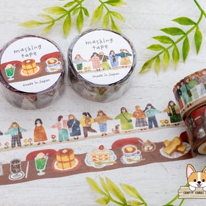 May include: Masking tape rolls with illustrated designs. One roll features people holding hands, the other has food and drink illustrations. The tape is brown with white text that says "masking tape" and "Made in Japan".