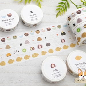 May include: Assortment of Japanese washi tape rolls featuring various food designs, including rice balls, fish cakes, and soup. The tape is white with colorful illustrations and the text "PAPIER PLATZ" on each roll.