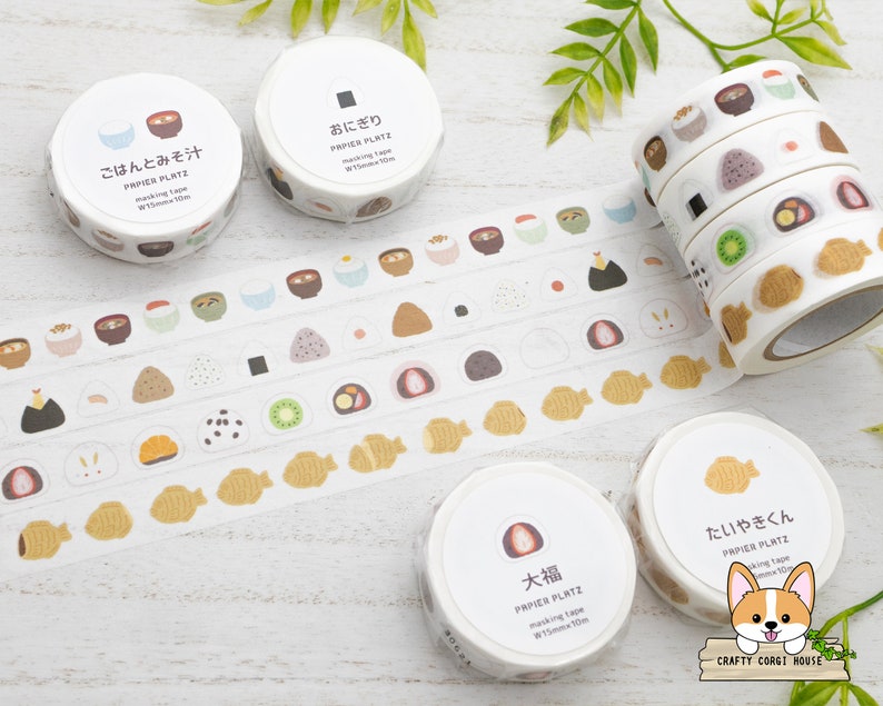 May include: Assortment of Japanese washi tape rolls featuring various food designs, including rice balls, fish cakes, and soup. The tape is white with colorful illustrations and the text "PAPIER PLATZ" on each roll.