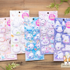 May include: Five sticker sheets featuring various cute cartoon characters in pastel colors. Each sheet has a different theme, including pandas, bunnies, and other whimsical designs. The stickers are packaged in clear plastic with Japanese text and a pink circular logo.