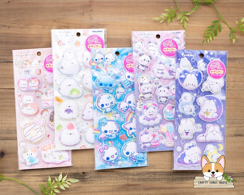 May include: Five sticker sheets featuring various cute cartoon characters in pastel colors. Each sheet has a different theme, including pandas, bunnies, and other whimsical designs. The stickers are packaged in clear plastic with Japanese text and a pink circular logo.