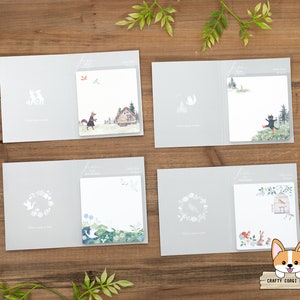 May include: Set of six gray memo pads with illustrated designs. Each pad features a different woodland animal or scene, including a fox, a bird, a cat, a birdcage, a wreath, and a house. The pads are all the same size and have a white background.