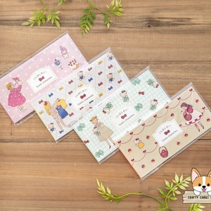 May include: Five colorful patterned notepads with Japanese text that reads "くらはしれい Sono characters". The notepads feature illustrations of girls and animals. The notepads are on a wooden surface.