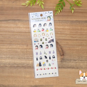 May include: A clear plastic package of schedule seal stickers. The stickers feature various illustrations of characters and objects. The text "Schedule SEAL" is printed at the top of the package. The stickers are on a wooden surface.
