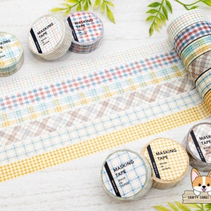 May include: Assortment of five rolls of patterned washi tape with the text "Masking Tape Made in Japan" on each roll. The tape features various plaid patterns in shades of blue, red, yellow, and brown.