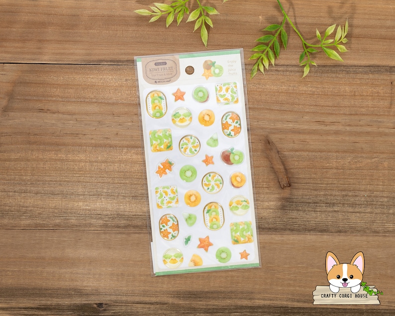 May include: A sheet of clear stickers with illustrations of kiwi fruit slices, kiwi fruit halves, and kiwi fruit stars. The stickers are on a white background with the text "Kiwi Fruit" in a brown rectangle.