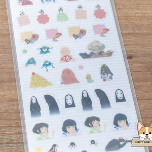 Op de afbeelding: Een vel met transparante stickers met personages en objecten uit de animatiefilm Spirited Away. De stickers bevatten No Face, Chihiro en andere personages uit de film.