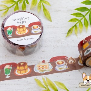 May include: A roll of masking tape with a brown cafe-themed design. The tape features illustrations of desserts and drinks, including pancakes, ice cream floats, and coffee. The label reads "masking tape" and "Made in Japan."