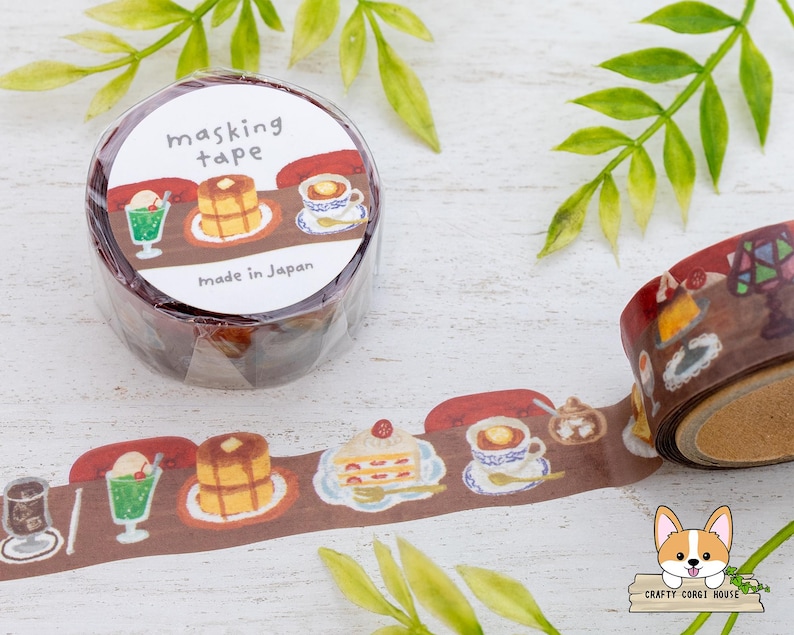 May include: A roll of masking tape with a brown cafe-themed design. The tape features illustrations of desserts and drinks, including pancakes, ice cream floats, and coffee. The label reads "masking tape" and "Made in Japan."
