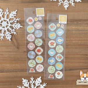 May include: Two packs of decorative stickers featuring floral and animal designs in a variety of colors. The stickers are in clear packaging with the text "NB CO., LTD JAPAN". The stickers are round and flower-shaped, with images of flowers, rabbits, and other decorative elements.
