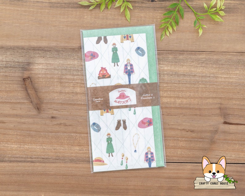 May include: A green and white envelope with a whimsical pattern of people, hats, and other objects. The envelope has the text "Letters & Envelopes 2" and "Totoro's Haystack" printed on it.