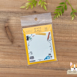 May include: A package of 30-sheet sticky notes with a yellow border and a grid pattern. The notes feature whimsical cat illustrations and Japanese text. A clear plastic bag holds the notes, set against a wooden background.