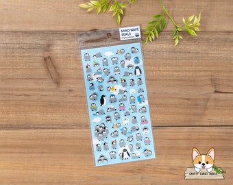 Op de afbeelding: Een vel stickers met verschillende schattige pinguïnontwerpen. De stickers zijn op een blauwe achtergrond en verpakt in een doorzichtige plastic zak. De tekst "Mind Wave Seals" staat op de zak gedrukt.