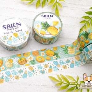 May include: Two rolls of washi tape with a tropical pineapple design. The tape is white with green leaves and yellow pineapples. The text on the tape reads "Saiien masking tape Tropical Pineapple".