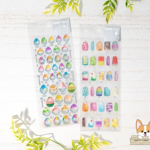 May include: Two sheets of clear sticker paper with colorful images of shaved ice and popsicles. The sticker sheets are labeled "Drop Seal".