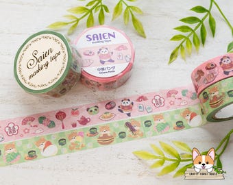 May include: Two rolls of Saien masking tape, one green and one pink, featuring illustrated patterns of pandas, shiba inu dogs, tea sets, and traditional symbols. The pink roll shows a panda, while the green roll displays a shiba inu dog design.