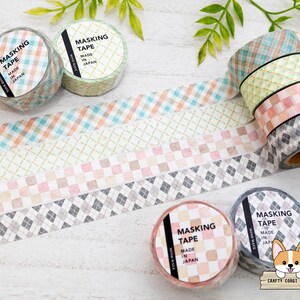 May include: A collection of decorative masking tape rolls with various plaid and checkered patterns in pastel colors. The rolls are labeled "MASKING TAPE MADE IN JAPAN". The tape designs include orange, blue, pink, green, and gray.