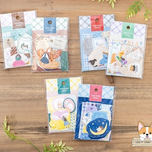 May include: Six packs of Yori-Dori stickers in clear plastic packaging, displayed on a wooden surface. The sticker packs feature illustrations of animals, food, and decorative elements. Each pack has a different colour scheme and a gingham pattern.