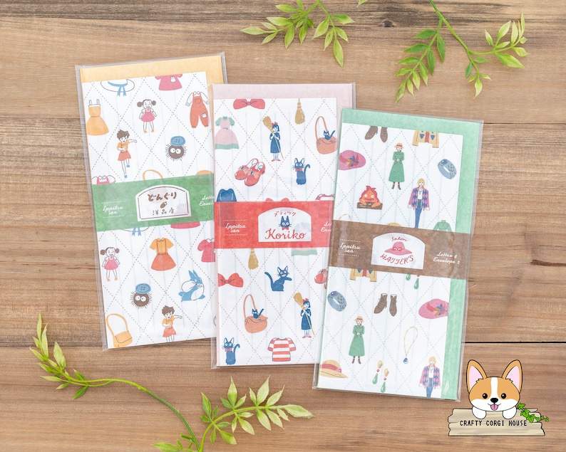 May include: Three colorful envelopes with a white background and a repeating pattern of a black cat, a witch, and a broom. The envelopes have a quilted texture and are decorated with a variety of other images, including a hat, a bag, and a shoe. The envelopes are labeled with the words "Koriiko", "Mayjers", and "Zenshin".
