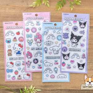 May include: Four sticker sheets featuring Hello Kitty, My Melody, Cinnamoroll, and Kuromi characters. Each sheet is in a clear plastic sleeve with a pink or blue border. The stickers include rainbows, hearts, and character illustrations.