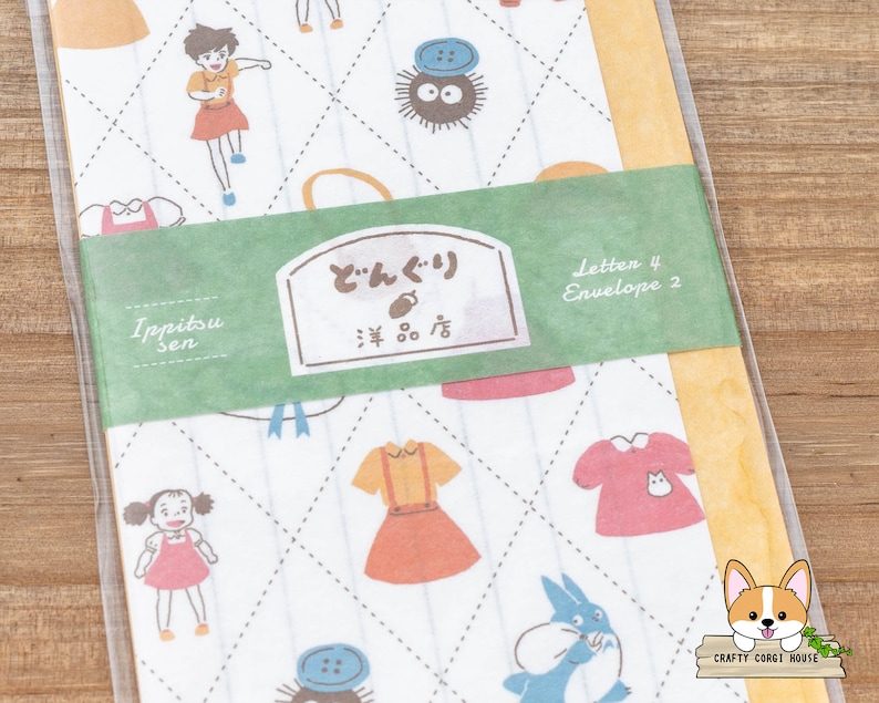 May include: A set of 4 letter paper and 2 envelopes with a white background and a repeating pattern of a blue and white character, a red and white dress, a yellow and red dress, a blue and black character, and a red and white dress. The paper and envelopes have a green border with the text "Ippitsu sen" and "どんぐり  雑貨店" in Japanese. The text "Letter 4 Envelope 2" is also on the green border.