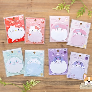 May include: A collection of eight character-shaped sticky note pads in various colors. Each pad features a different cartoon character design, including Hello Kitty and other characters. The pads are packaged in clear plastic with Japanese text.
