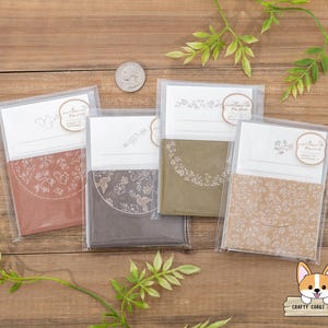Op de afbeelding: Vier verschillende blanco wenskaarten met bloemmotieven. De kaarten zijn in bruin, groen en wit.