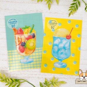 May include: Two illustrated cards with a yellow and blue background. The first card features a glass of fruit salad with a blue and white checkered background. The second card features a glass of blue shaved ice with a cherry on top and a yellow background with blue polka dots. Both cards have the text "レモン グラス" in Japanese.