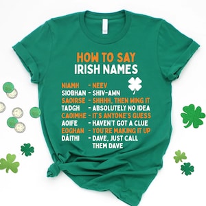 May include: Green t-shirt with white text that says "How to Say Irish Names" and a list of Irish names with their pronunciations. The names are in orange text and the pronunciations are in black text. There are shamrock graphics on the shirt.