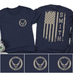 Op de afbeelding: Een marineblauw t-shirt met een cirkelvormig Air Force-logo op de linkerborst met de tekst Proud Mom, Proud Dad, Proud Sister of Proud Brother. De achterkant toont een verweerde Amerikaanse vlag met de verticale tekst SMITH.